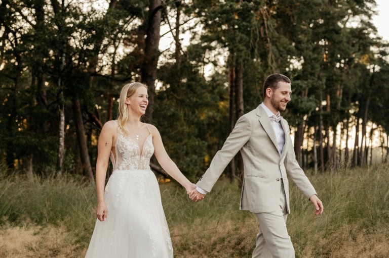Hochzeitspaar läuft Hand in Hand im Grünen Wald, romantische Naturfotografie für Hochzeitsfotos.